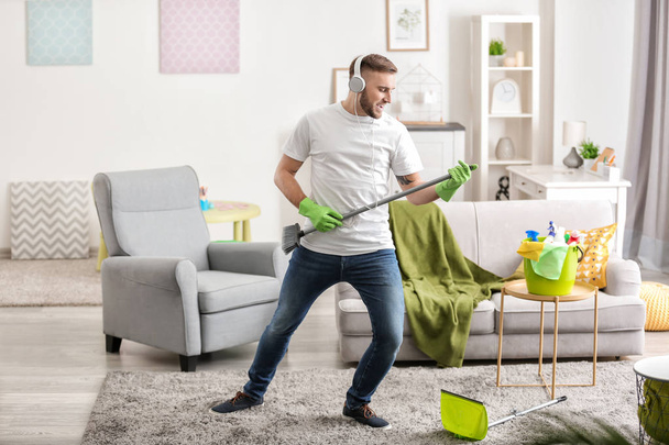 Young man having fun while cleaning his flat - Foto, Bild