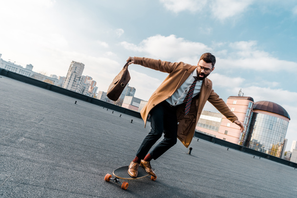 excitado hombre de negocios cabalgando en penny board con bolsa en la mano
  - Foto, imagen
