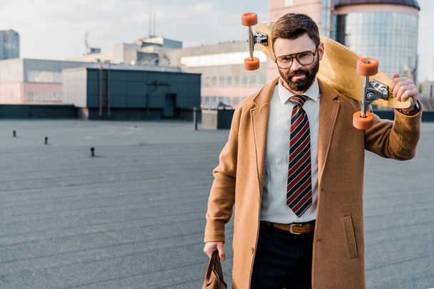 uomo d'affari di successo in piedi in occhiali con penny board in mano
  - Foto, immagini