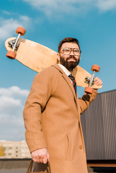 smiling businessman in glasses holding penny board  - Foto, afbeelding