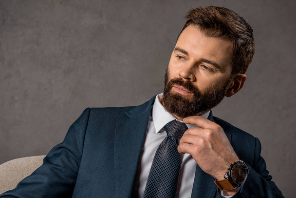 close up of pensive businessman in formalwear with watch on hand  - Fotó, kép