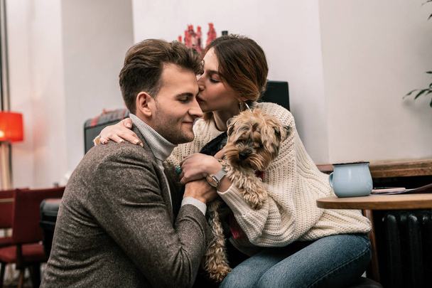 Woman kissing her partner while holding the dog - Photo, image