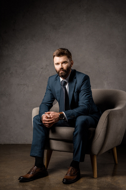 handsome bearded businessman sitting in armchair  - Zdjęcie, obraz