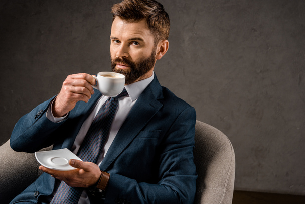 successful businessman drinking coffee and holding saucer - Fotoğraf, Görsel