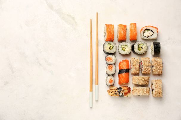 Samenstelling met lekkere sushi op lichte achtergrond - Foto, afbeelding