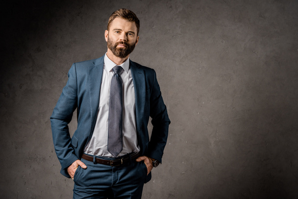 handsome bearded businessman standing in formalwear with hands in pockets   - Photo, image