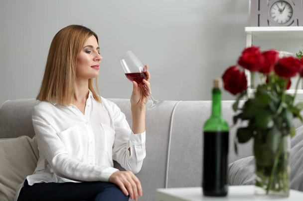 Mooie vrouw met glas rode wijn thuis - Foto, afbeelding