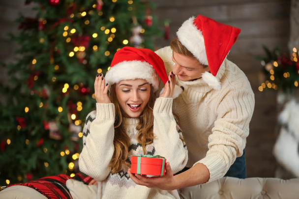 Молодая женщина получает рождественский подарок от своего парня дома
 - Фото, изображение