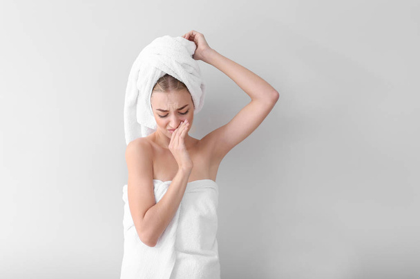Piękna młoda kobieta po prysznicem uczucie zapach potu na jasnym tle. Koncepcja wykorzystania dezodorant - Zdjęcie, obraz