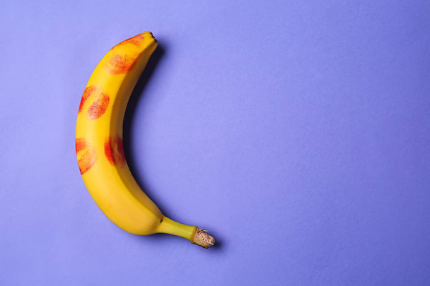 Свежий банан с отпечатками помады на цветном фоне. Эротическая концепция - Фото, изображение