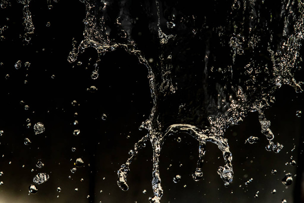 Vesi roiskuu pimeässä vesipisaroiden lentäessä, defocused bokeh
. - Valokuva, kuva