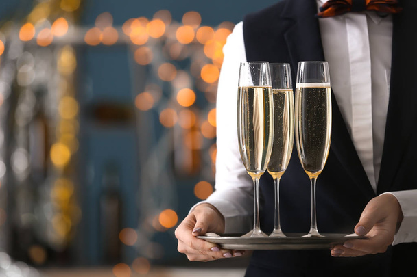 パーティーでシャンパンのグラスとトレイを保持しているウェイトレス - 写真・画像