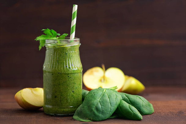 Green spinach smoothies in glass with ingredients on dark wooden table. Side view. - Zdjęcie, obraz