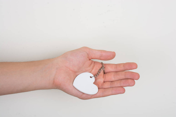 Καρδιά σχήμα λευκό αντικείμενο στο χέρι σε λευκό φόντο - Φωτογραφία, εικόνα