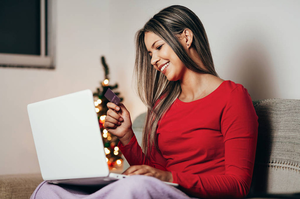 Young woman ordering Christmas gifts online at home - Photo, image
