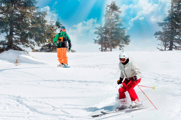 Skiërs en snowboarders rijden op een ski-oord op winter van de besneeuwde berg met fir-tree achtergrond schilderachtig uitzicht. - Foto, afbeelding