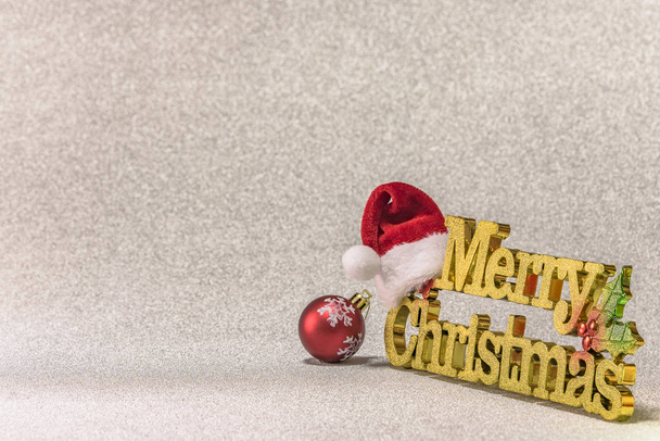 Αϊ Βασίλη καπέλο, θέσει σε μια χρυσή λέξη καλά Χριστούγεννα με ένα χριστουγεννιάτικο δέντρο νιφάδες χιονιού μοτίβο στολίδι μπάλα σε φόντο χιόνι ασημένια λάμψη. - Φωτογραφία, εικόνα