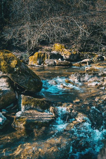 Ένα ορμητικό ποτάμι που ρέει μέσα από μεγάλα βράχια με βρύα - Φωτογραφία, εικόνα