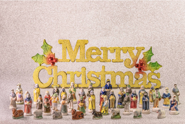 Kleine beeldjes van santons uit de Franse Provence gebruikt als bonen van de cake van de koningen tijdens de Driekoningen ook teruggebeld de Little Christmas met in het gouden woord Merry Christmas. - Foto, afbeelding