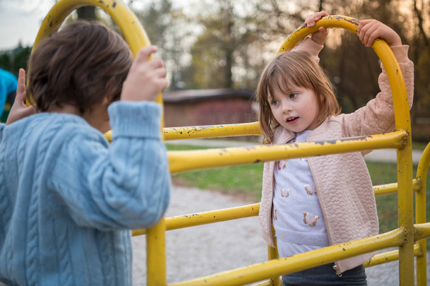 cutte petite fille et garçon dans le parc pour enfants avoir du plaisir et de la joie tout en jouant dans l'aire de jeux sur la journée nuageuse d'automne
 - Photo, image