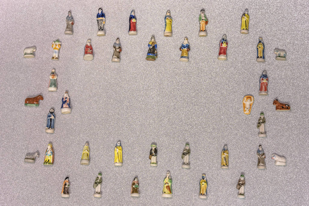 Małe figurki santons z francuskiej Prowansji używane jak fasola ciasto królów podczas trzech króli, zwany także Little Christmas na tle srebrnym śnieg świecidełka. - Zdjęcie, obraz