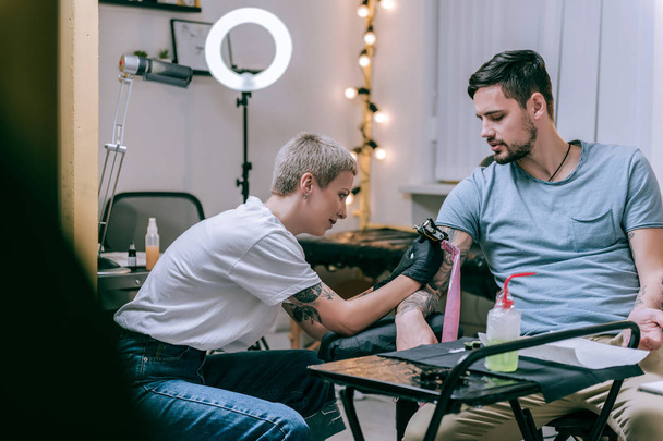 Smiling attentive professional tattoo master working with unfinished tattoo - Zdjęcie, obraz