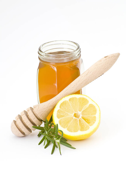 purkki hunajaa, sitruuna ja puinen tihkusade eristetty valkoisella pohjalla
 - Valokuva, kuva