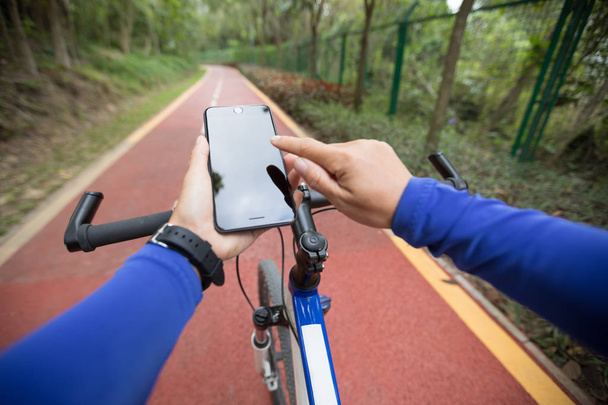 Cyclist using smartphone app for navigation while bike ride on the forest trail - Zdjęcie, obraz