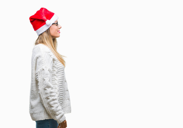 junge schöne Frau trägt Weihnachtsmütze über isoliertem Hintergrund mit Blick zur Seite, entspannen Profil Pose mit natürlichem Gesicht mit selbstbewusstem Lächeln. - Foto, Bild