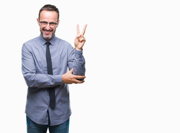 Middle age hoary senior business man wearing glasses over isolated background smiling with happy face winking at the camera doing victory sign. Number two. - Valokuva, kuva