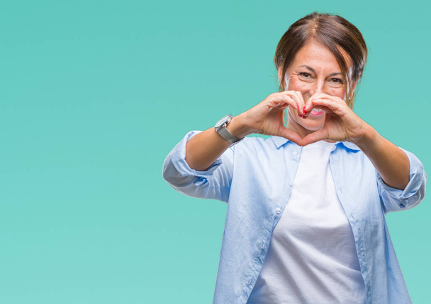 Middelbare leeftijd senior Latino vrouw over geïsoleerde achtergrond glimlachend in liefde met hartsymbool en vorm met de handen. Romantische concept. - Foto, afbeelding