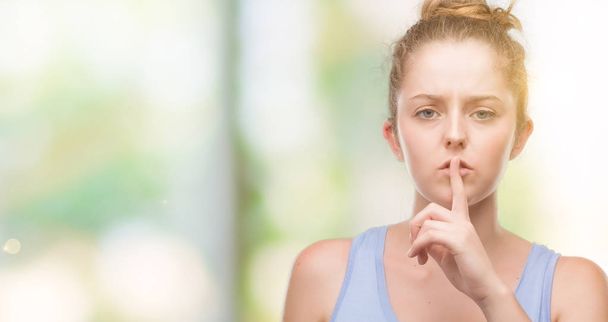 Jeune femme blonde demandant à se taire avec le doigt sur les lèvres. Silence et concept secret
. - Photo, image