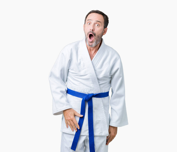 Handsome middle age senior man wearing kimono uniform over isolated background In shock face, looking skeptical and sarcastic, surprised with open mouth - Photo, Image