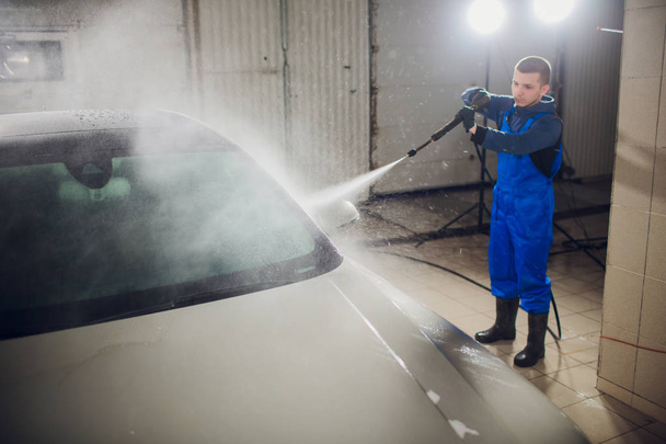 man washing automobile manual car washing self service,cleaning with foam,pressured water. Transportation care concept. Washing car in self service station with high pressure blaster - Zdjęcie, obraz