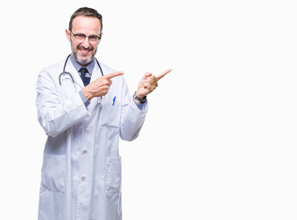 Старший седовласый врач средних лет, одетый в медицинскую униформу, улыбается и смотрит на камеру, указывая двумя руками и пальцами в сторону.
. - Фото, изображение