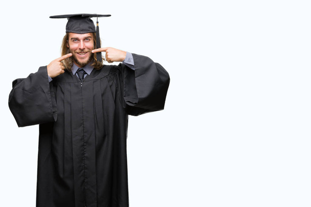 Young handsome graduated man with long hair over isolated background smiling confident showing and pointing with fingers teeth and mouth. Health concept. - Photo, Image