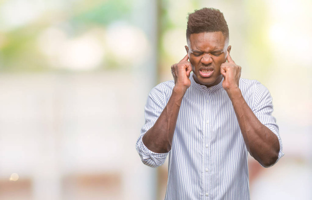 Mladý americký muž izolované pozadí pokrývající uši prsty s otrávený výraz pro hluk z hlasité hudby. Neslyšící koncepce. - Fotografie, Obrázek