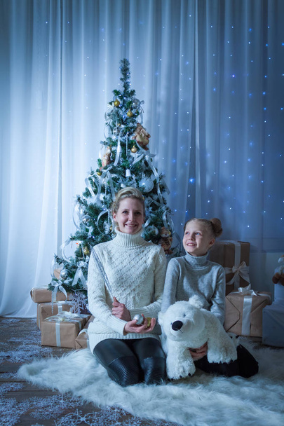 Красива жінка і її дочка біля новорічної ялинки
 - Фото, зображення