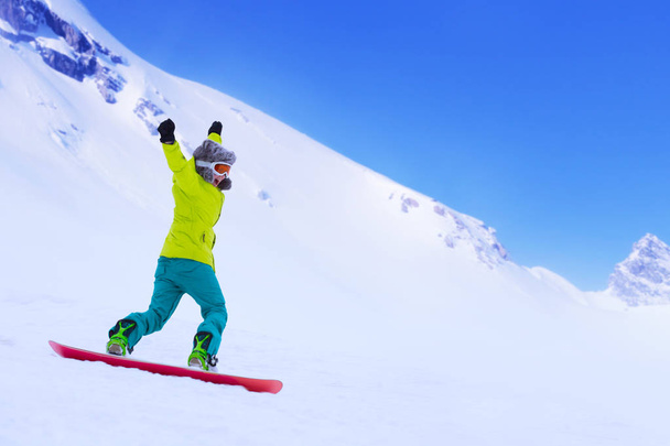 Girl snowboarder running down the slope in Alpine mountains. Winter sport and recreation, leisure outdoor activities. Image of excited screaming young woman enjoyment concept - 写真・画像