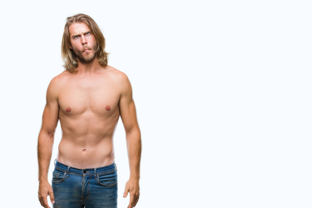 Young handsome shirtless man with long hair showing sexy body over isolated background making fish face with lips, crazy and comical gesture. Funny expression. - Photo, Image