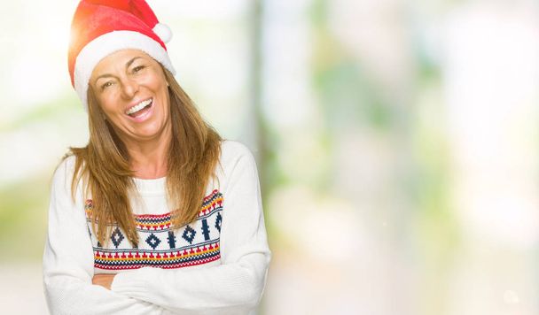 Donna adulta di mezza età che indossa maglione invernale e cappello chrismat su sfondo isolato volto felice sorridente con le braccia incrociate guardando la fotocamera. Persona positiva
. - Foto, immagini