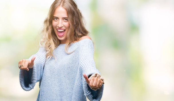 Beautiful young blonde woman wearing winter sweater over isolated background approving doing positive gesture with hand, thumbs up smiling and happy for success. Looking at the camera, winner gesture. - Fotografie, Obrázek
