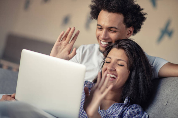 Cheerful happy African American young marriage laughing while watching movie on laptop computer at home interior. - Foto, afbeelding
