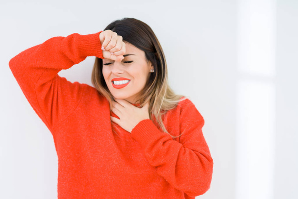 junge Frau in lässigem roten Pullover über isoliertem Hintergrund, die Stirn anrührend für Krankheit und Fieber, Grippe und Erkältung, Viruserkrankung - Foto, Bild