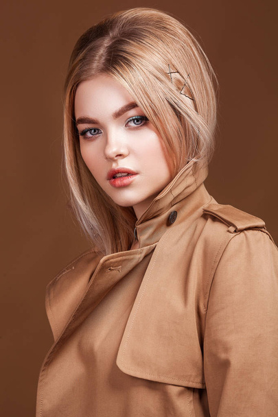 Portrait of young beautiful woman in trendy trench coat over beige background. Elegant fashion look. - Foto, immagini
