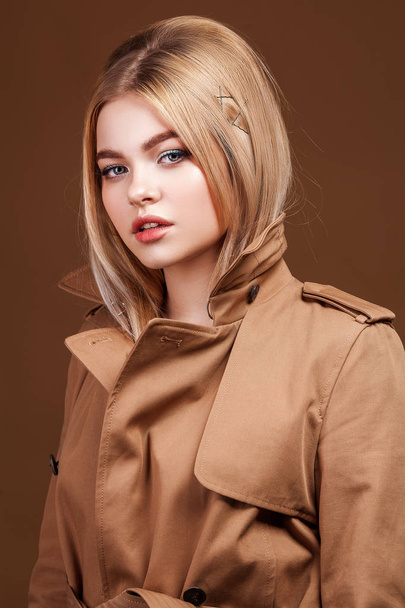 Portrait of young beautiful woman in trendy trench coat over beige background. Elegant fashion look. - Fotoğraf, Görsel