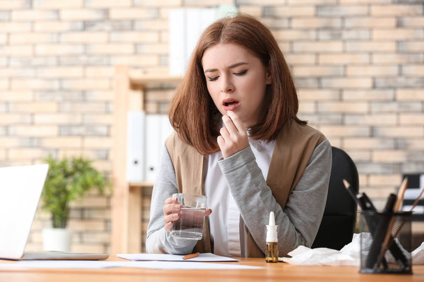 Молода жінка, хвора грипом, приймає ліки в офісі
 - Фото, зображення