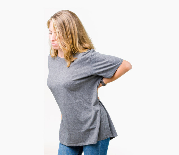 Krásná mladá žena nosí oversize ležérní tričko přes izolované pozadí utrpení z bolesti zad, dotykem s rukou, svalové bolesti - Fotografie, Obrázek