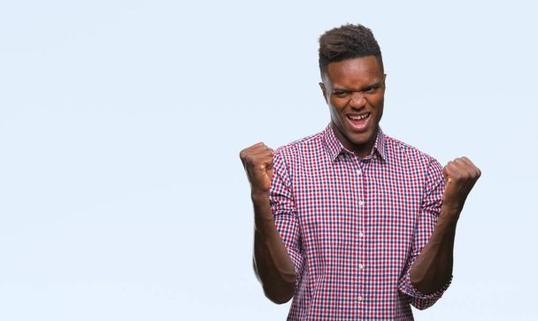 Jonge Afro-Amerikaanse man over geïsoleerde achtergrond erg blij en opgewonden doet winnaar gebaar met armen naar voren gebracht, glimlachen en schreeuwen voor succes. Viering concept. - Foto, afbeelding