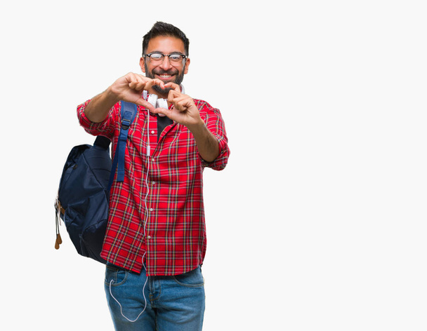 Дорослий іспаномовний студент у навушниках та рюкзаку над ізольованим тлом, посміхаючись у любові, показуючи символ серця та форму руками. Романтична концепція
. - Фото, зображення